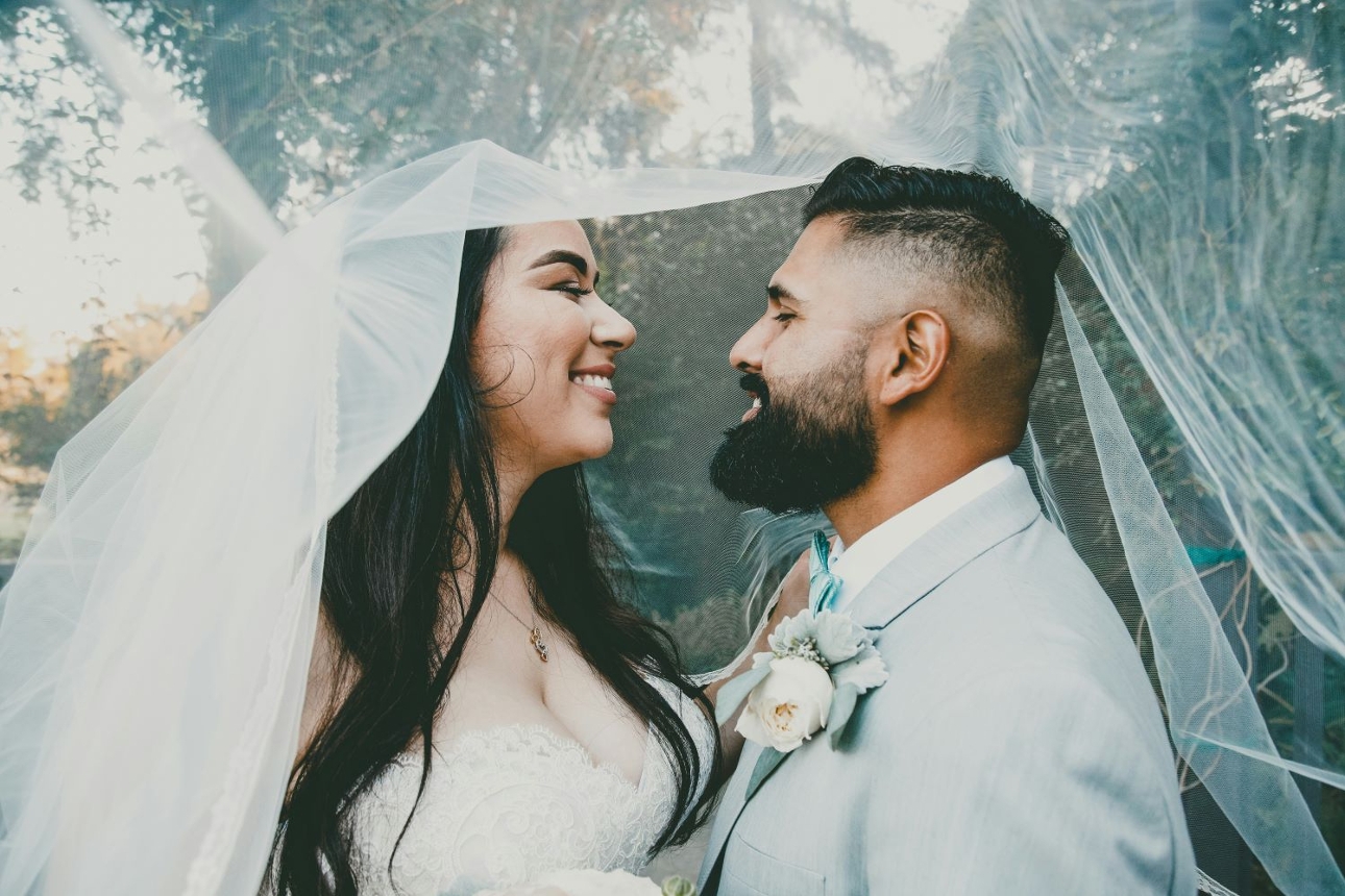 wedding couple under a veil embracing head to head