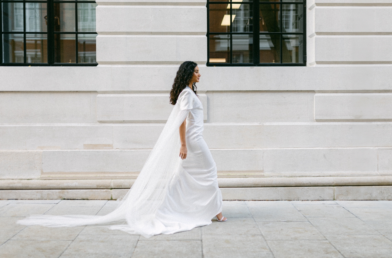 woman walking down street in bridal dress with long train