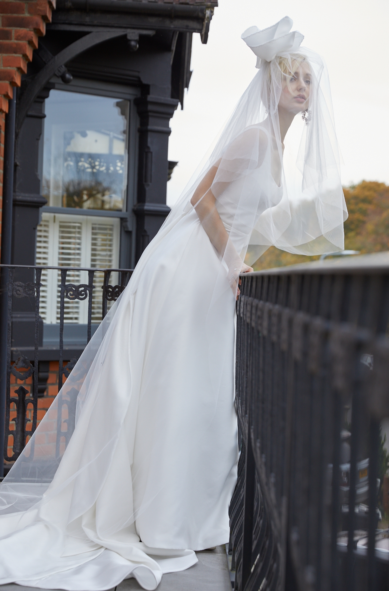 model in a line dress, on balcony, with tiered veil high on head