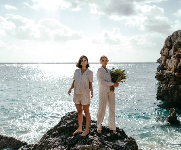 Two models in ivory pajamas on a rock