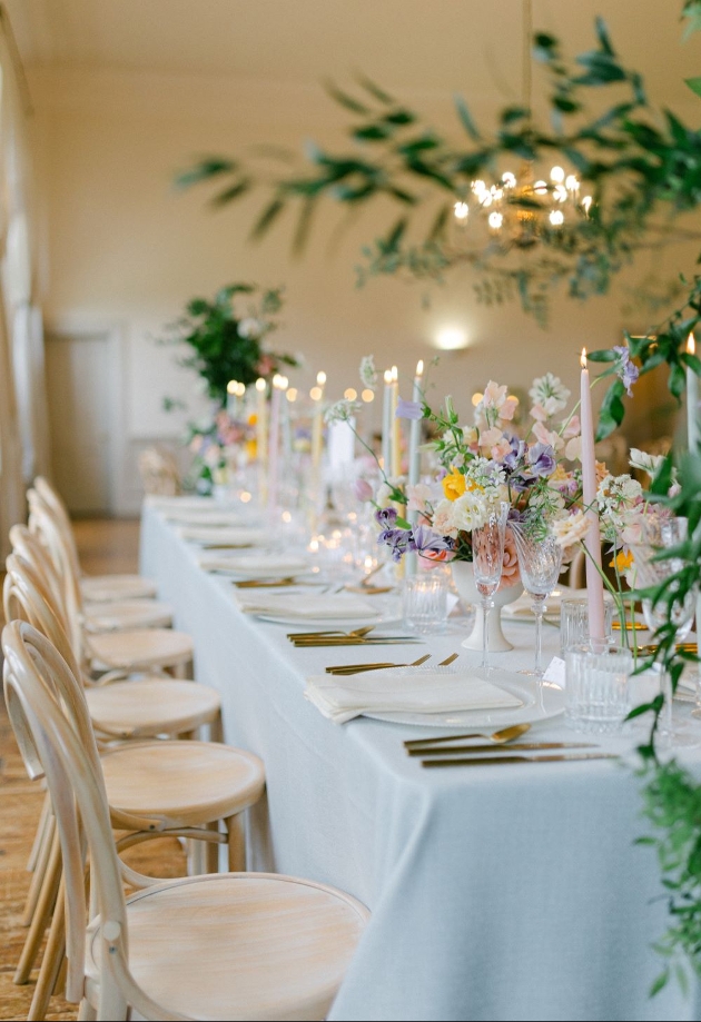 long table set out for wedding reception with pastel flowers down centre
