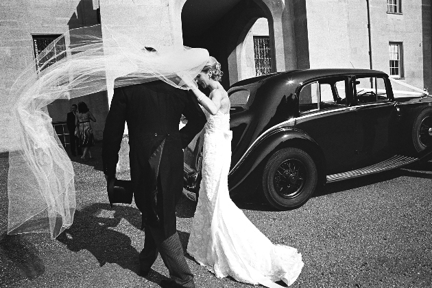 black and white image of a bride and groom getting in a care