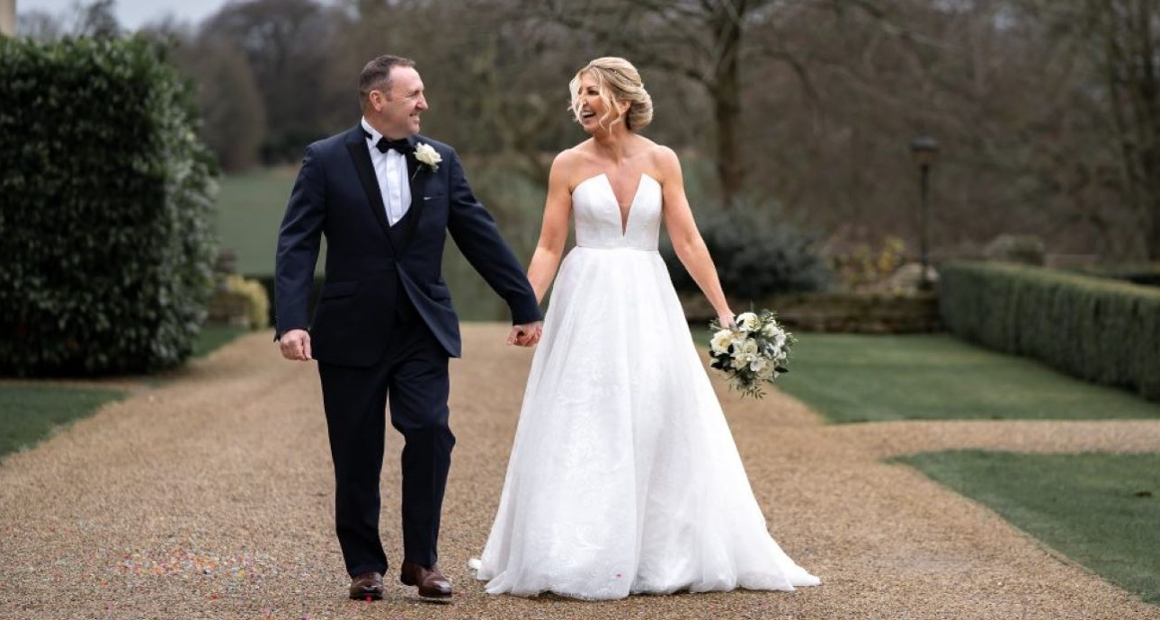 bride and groom waking alongside country house