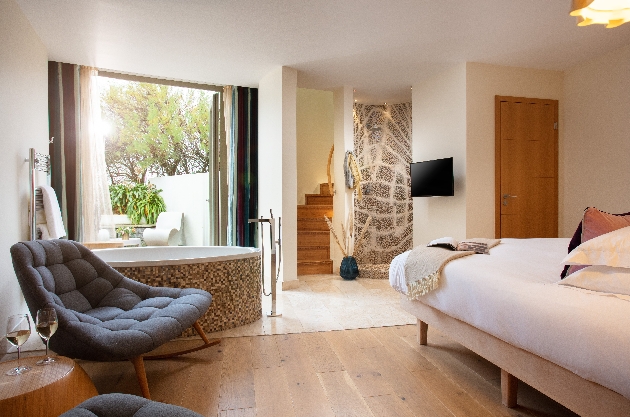 bedroom with jacuzzi, outside space, stairs to another room