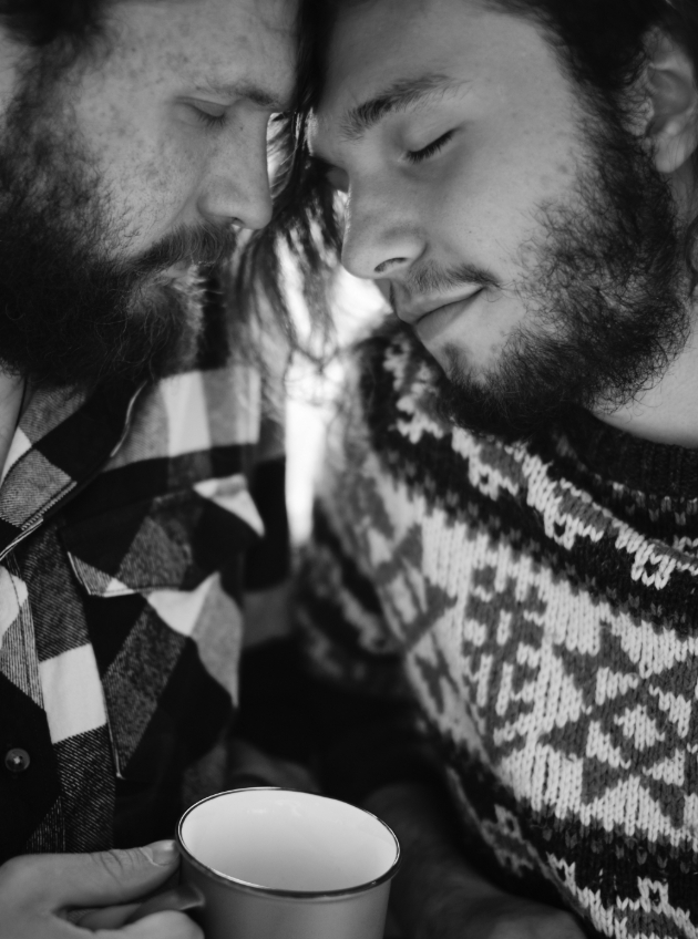 two men in jumpers with mugs touching heads